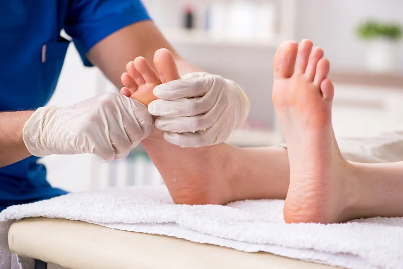 foot-reflexology-toronto-30min-pedicure-salon Gloved esthetician grooming a client’s toes during a dry pedicure in Toronto, Ontario